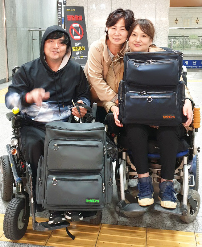 The founder of Feeldom, Mikyoung "Julia" Kim, with two users of the Feeldom wheelchair bag.